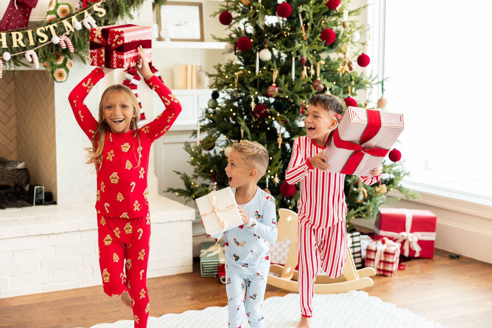 3 kids running with christmas presents in kyte baby christmas pajamas